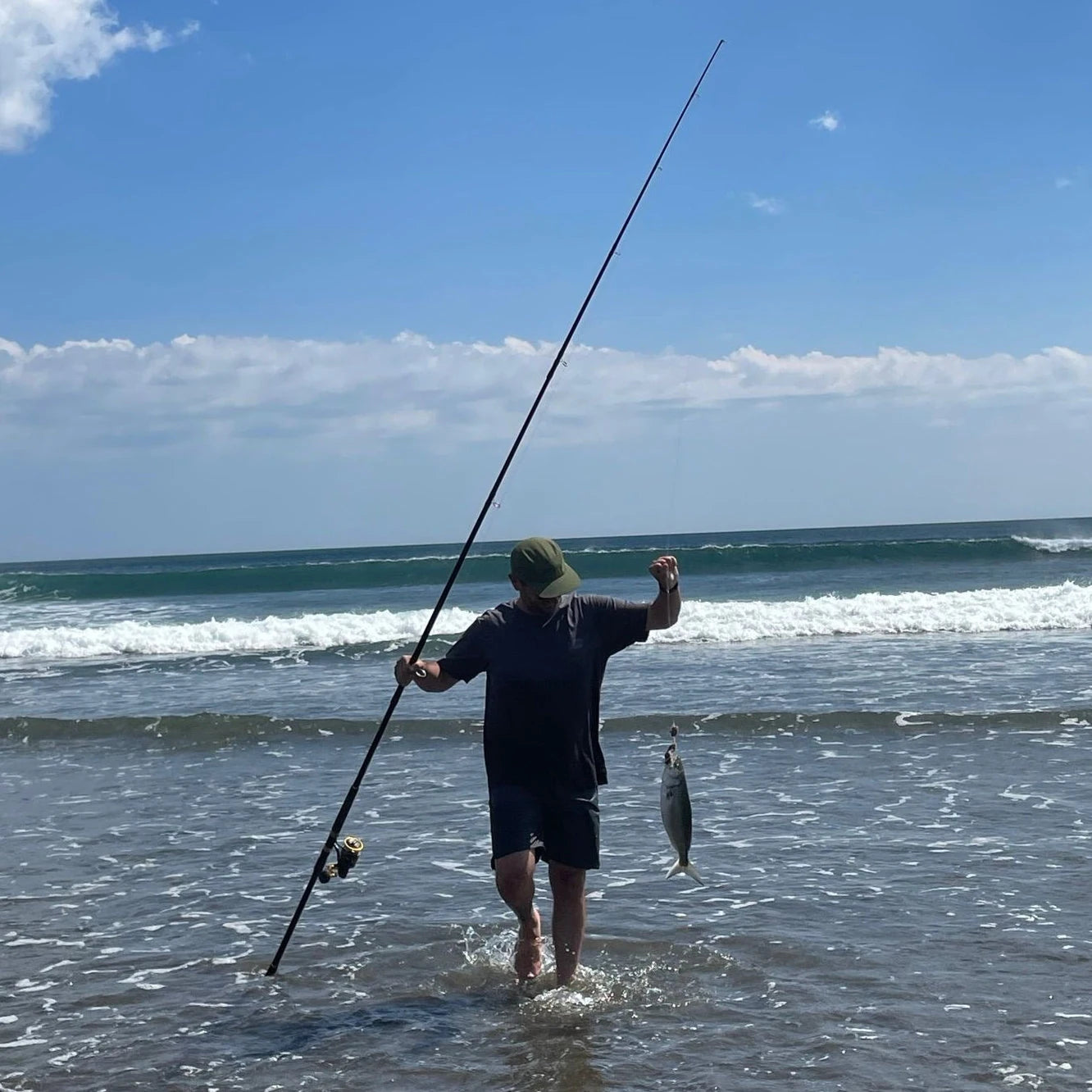 Angler surfcasting with a fish on the beach