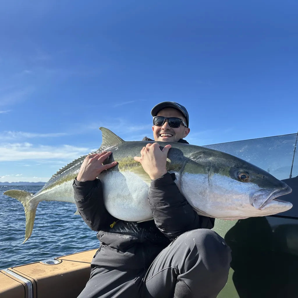 Angler holding a big kingfish on a boat