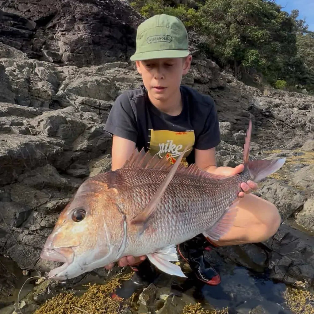 Young angler with a snapper in a rock pool